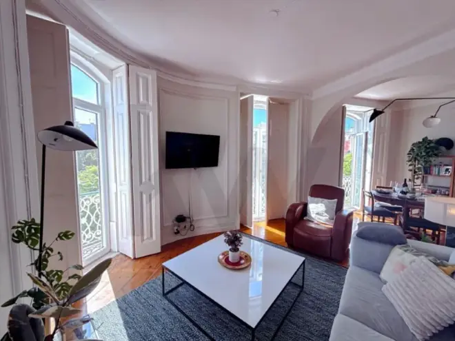 Living room with tall ceilings and arched double doors in a Pombaline Lisbon apartment